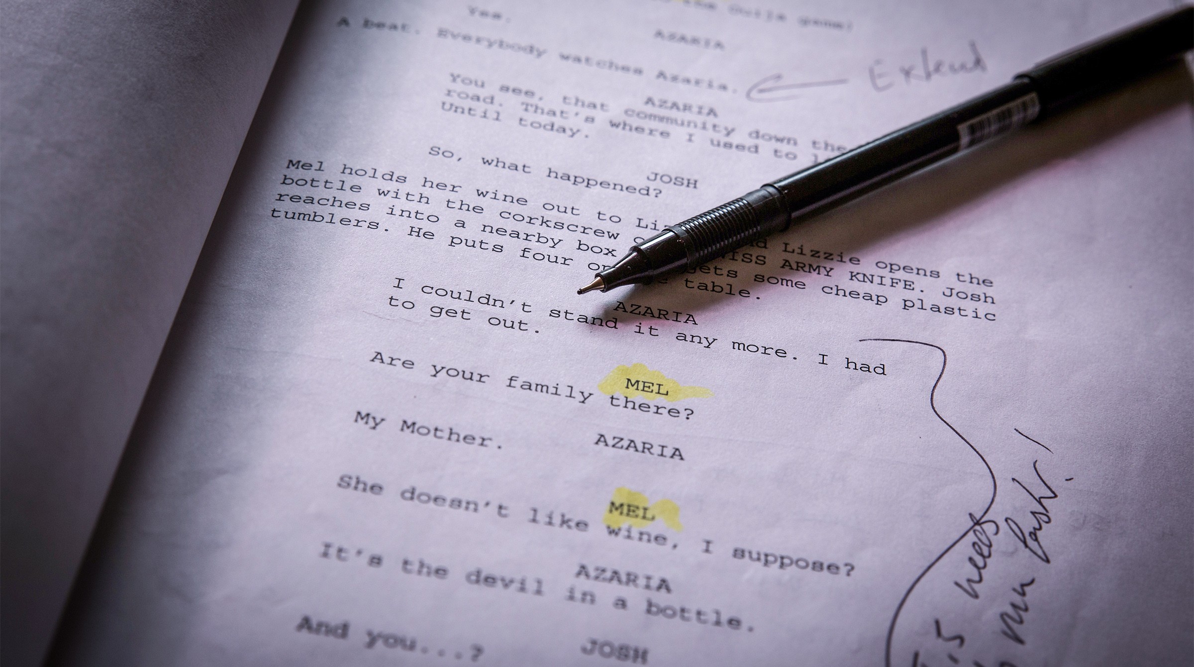 A screenplay page with handwritten notes and a pen.
